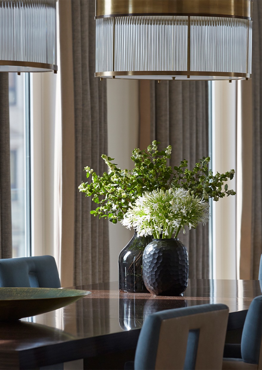 Luxury dining table with pendant lighting and green flower arrangements.