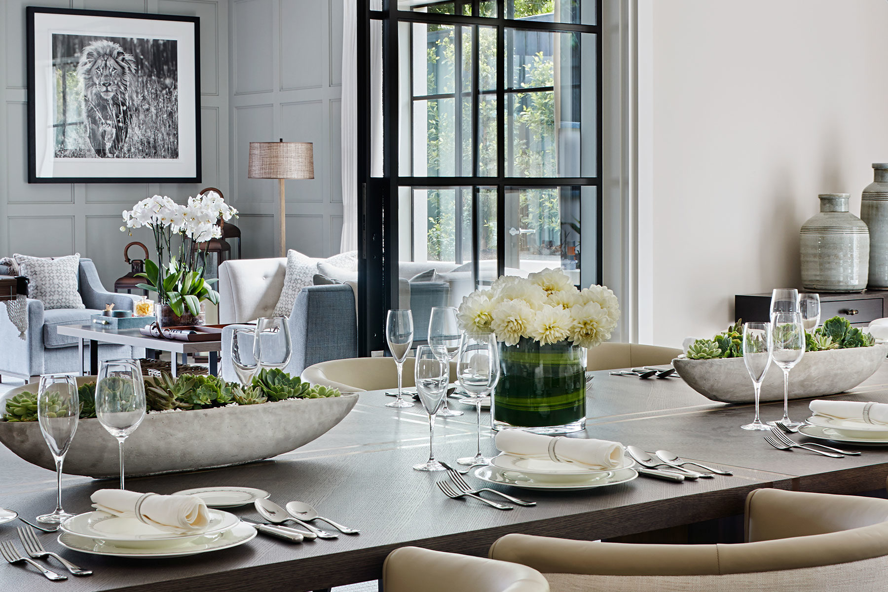 Wooden dining table with brass inlay and formal place settings dressed with cactus planters and fresh white dahlias.